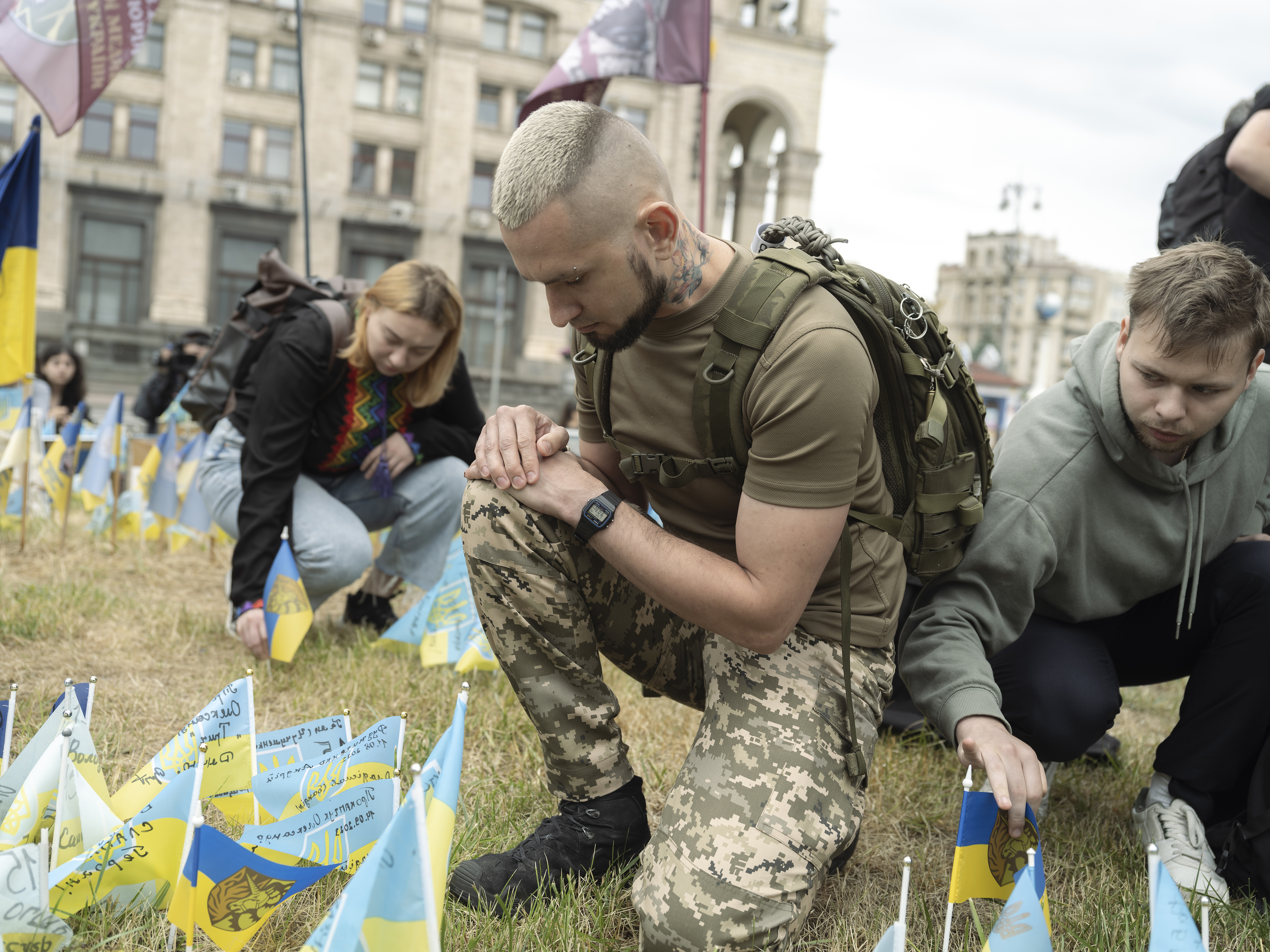 People kneeling down in front of Ukraine flags