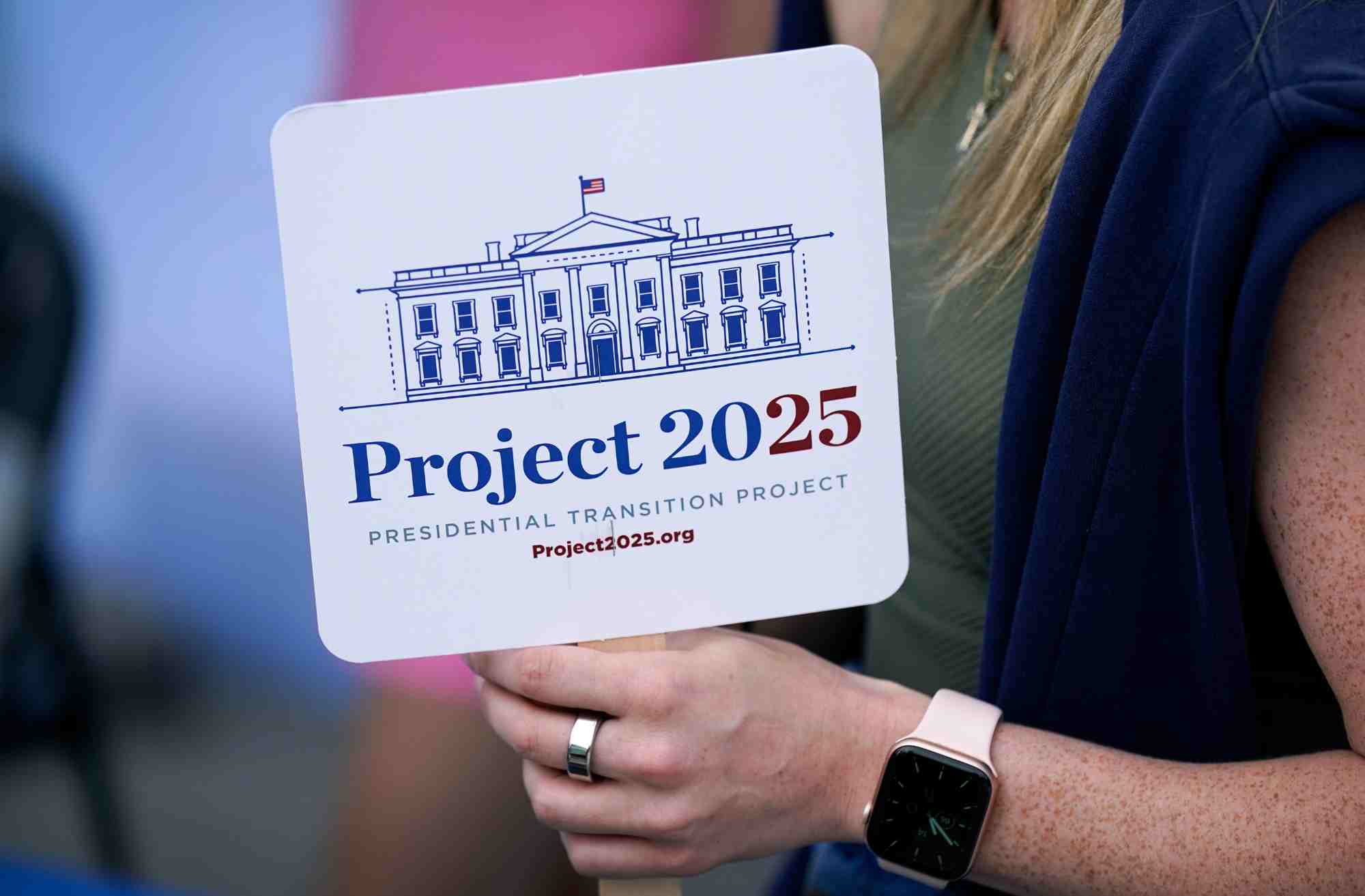 A woman holding a sign saying "Project 2025. Presidential Transition Project"