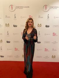 Valbona Zeneli at the Inspiration Awards Gala on a red carpet, holding the award