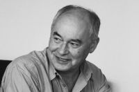 A black and white headshot of Martin Krol, looking away from the camera, smiling